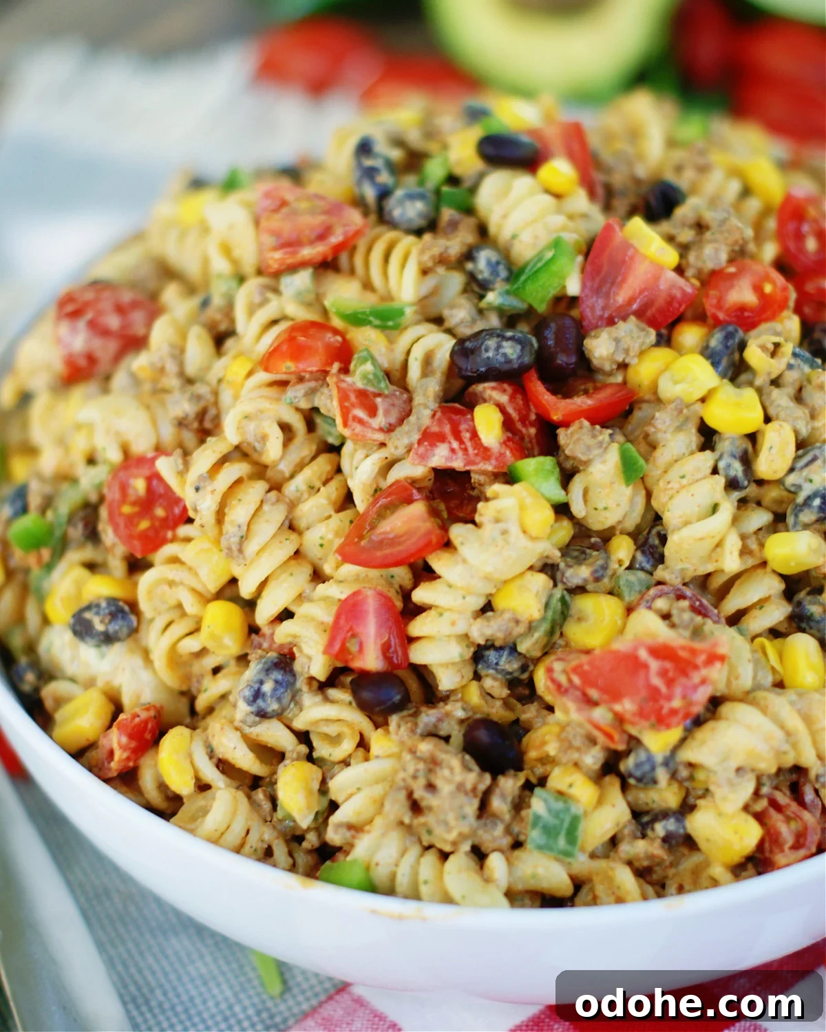Taco Pasta Salad with Creamy Avocado Dressing 2 Tex Mex Pasta Salad is loaded with seasoned ground beef, black beans, tomatoes, green onions, corn and jalapenos, then tossed in a cool, creamy avocado cilantro dressing with lime.