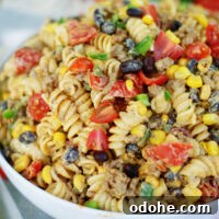 Tex Mex Pasta Salad is loaded with seasoned ground beef, black beans, tomatoes, green onions, corn and jalapenos, then tossed in a cool, creamy avocado cilantro dressing with lime.