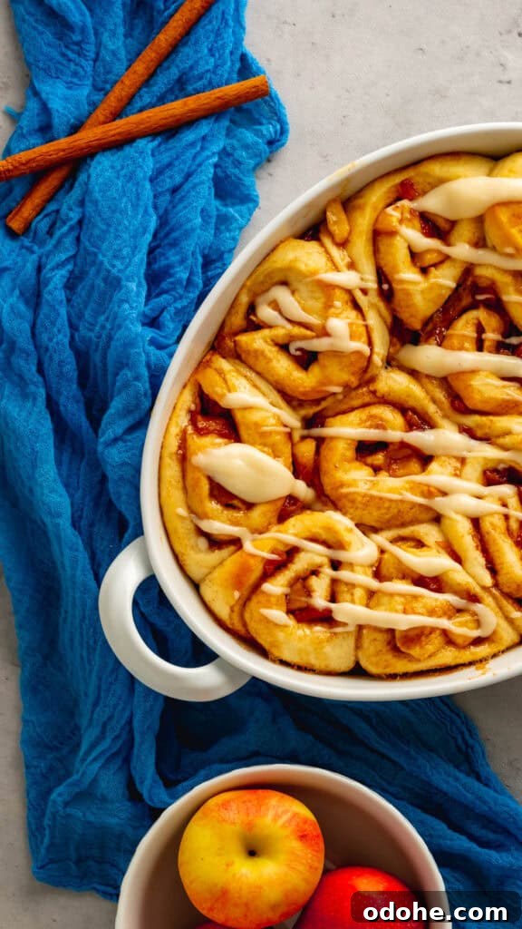 Apple Cider Cinnamon Rolls with Maple Glaze Recipe 2 An oval baking dish with apple cider cinnamon rolls with a cream cheese icing.