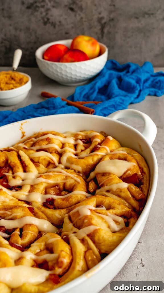 Apple Cider Cinnamon Rolls with Maple Glaze Recipe 4 Apple cider cinnamon rolls baked in a white oval baking dish topped with a sweet cream cheese glaze.