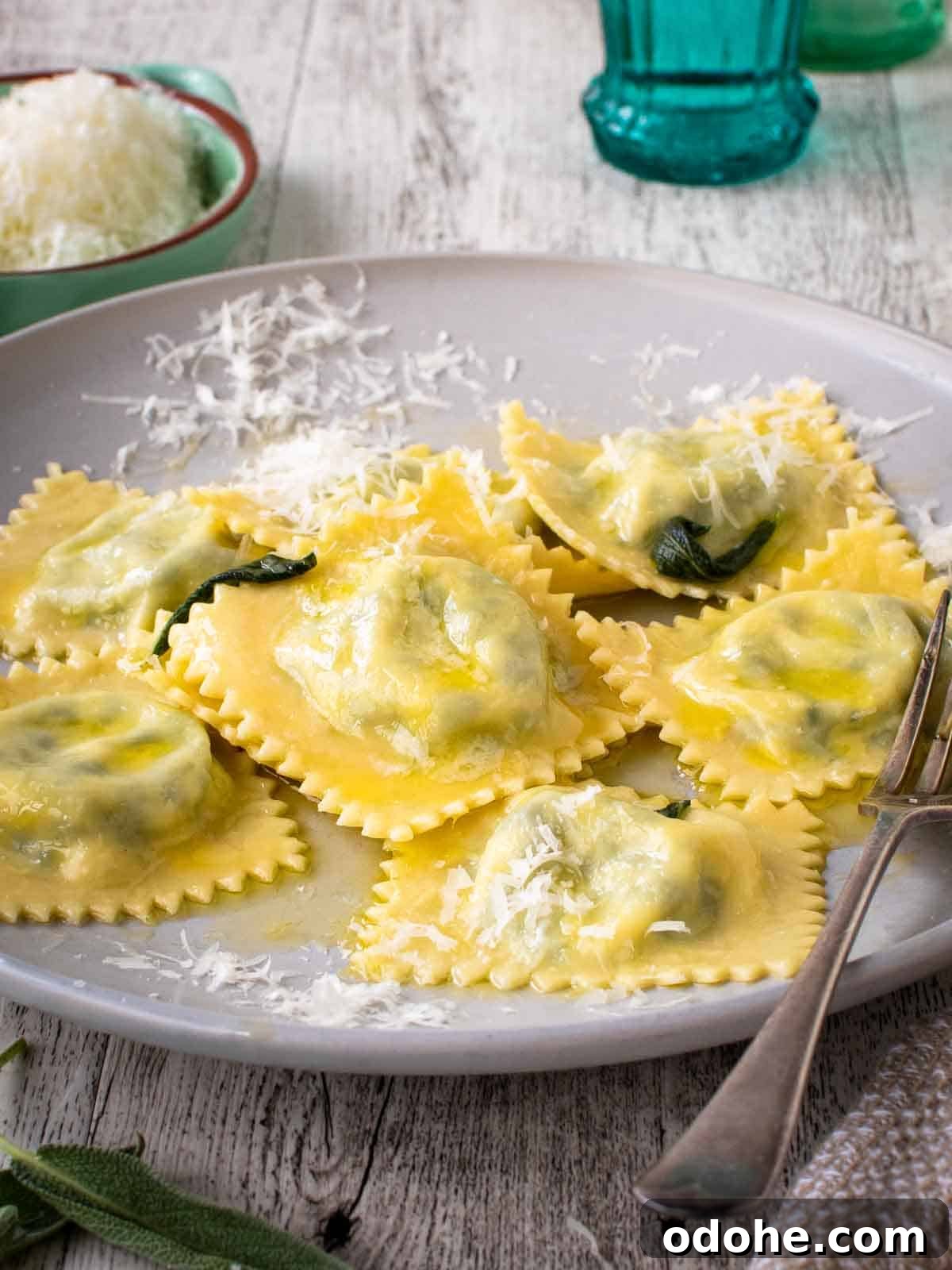 Fresh Spinach and Ricotta Ravioli Recipe for Homemade Pasta 2 Spinach Ricotta ravioli on a off white plate with a sprinkle of finely grated cheese.
