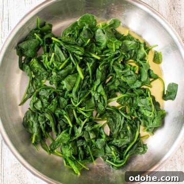 Fresh Spinach and Ricotta Ravioli Recipe for Homemade Pasta 4 Overhead view of spinach being cooked in a stainless steel pan.