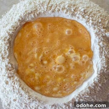 Fresh Spinach and Ricotta Ravioli Recipe for Homemade Pasta 6 Overhead view of beaten eggs in the middle of a well of flour.
