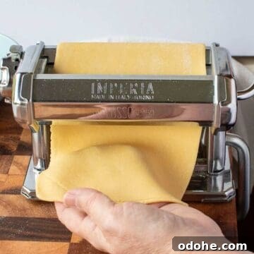 Fresh Spinach and Ricotta Ravioli Recipe for Homemade Pasta 10 Pasta dough being rolled through the rollers of a hand cranked pasta machine.