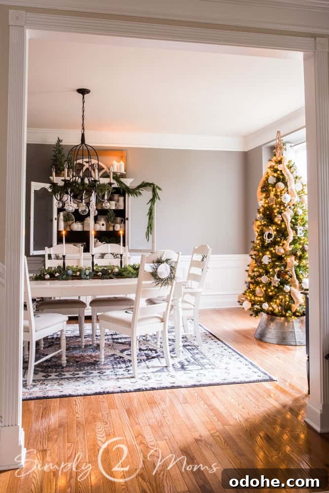 13 Timeless Neutral Christmas Decorating Ideas for Your Home 13 dining room table on rug with china cabinet behind and christmas tree in front of window