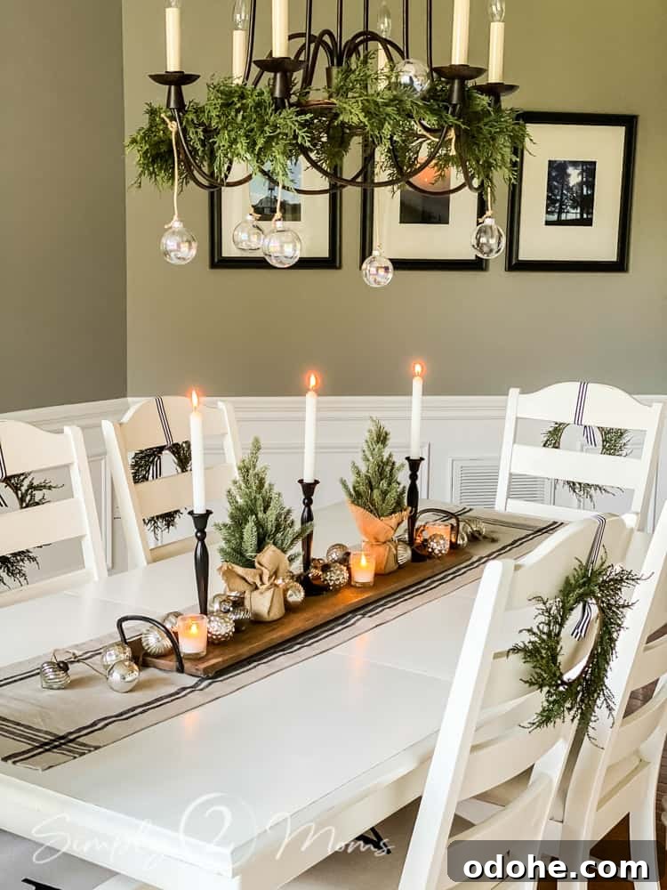 13 Timeless Neutral Christmas Decorating Ideas for Your Home 3 dining room table with mini trees and candles in center of table garland on chandelier