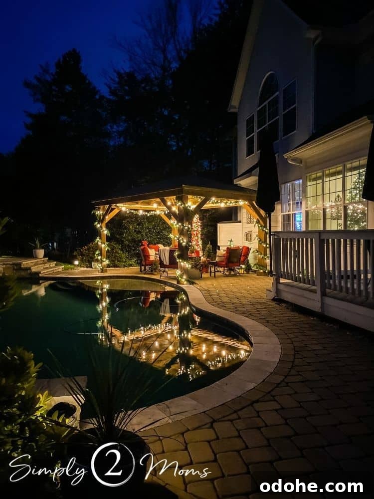 13 Timeless Neutral Christmas Decorating Ideas for Your Home 20 Patio with Pergola decorated for Christmas with greenery and lights on the pergola. Seating area with red cushions, tables with candle lanterns, and outdoor TV.