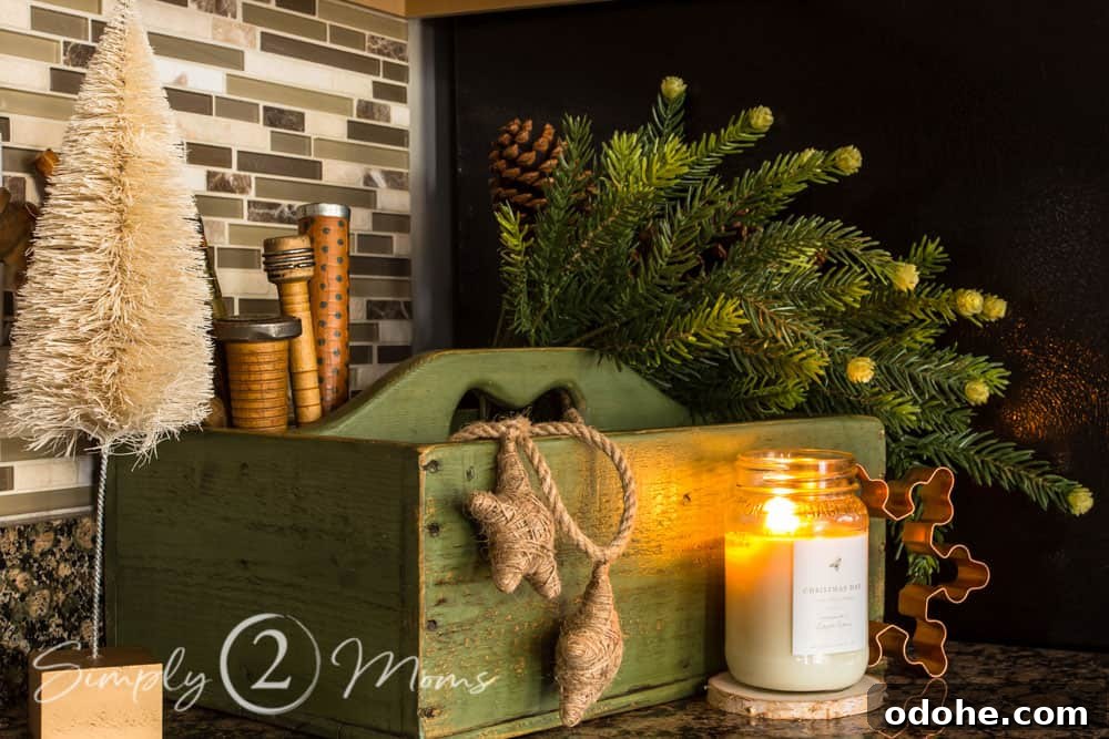 13 Timeless Neutral Christmas Decorating Ideas for Your Home 5 Vintage green tool box with faux greenery, vintage spools, and a jute star garland on a counter with a lit mason jar candle sitting in front