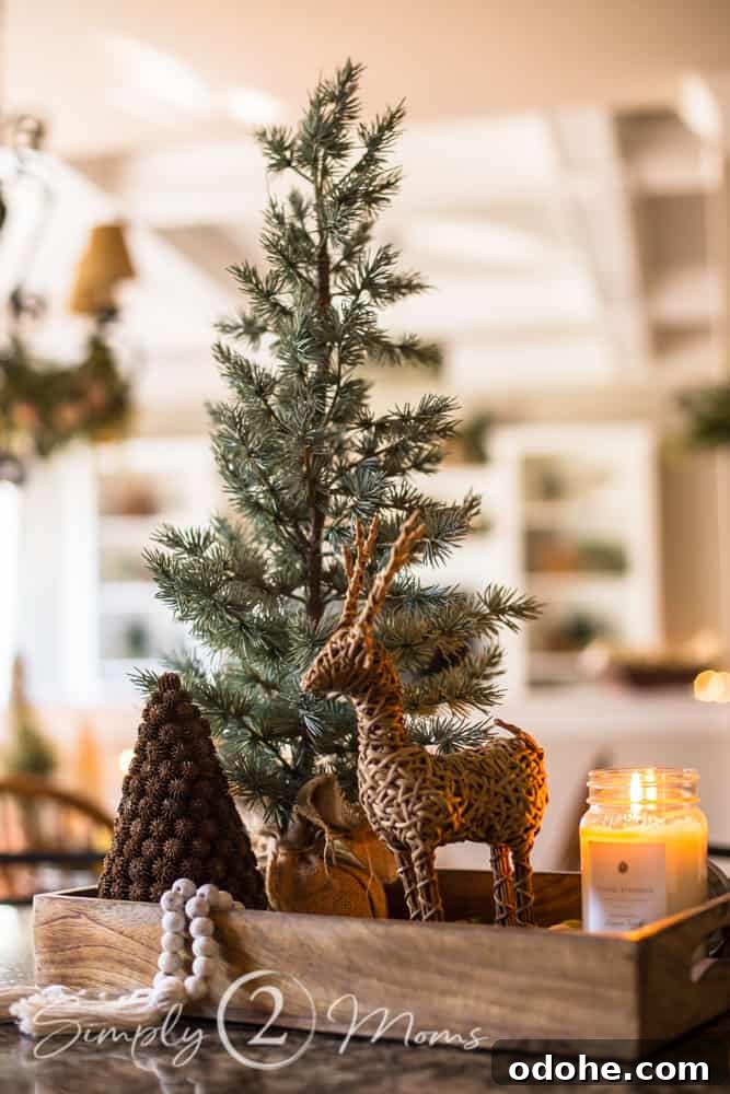 13 Timeless Neutral Christmas Decorating Ideas for Your Home 9 Wood tray sitting on a kitchen island filled with a mini tree, grapevine reindeer, tiny pinecone tree, and a lit mason jar candle