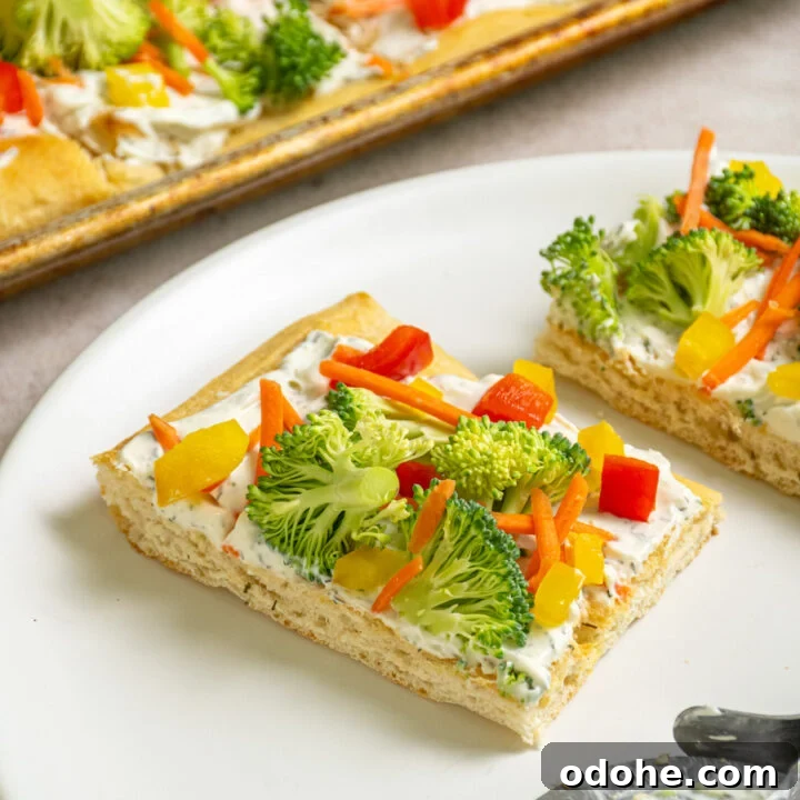 A slice of veggie pizza with broccoli, carrots, and bell pepper on a white plate.