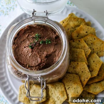 Chicken live pate on a glass jar with crackers on the side.