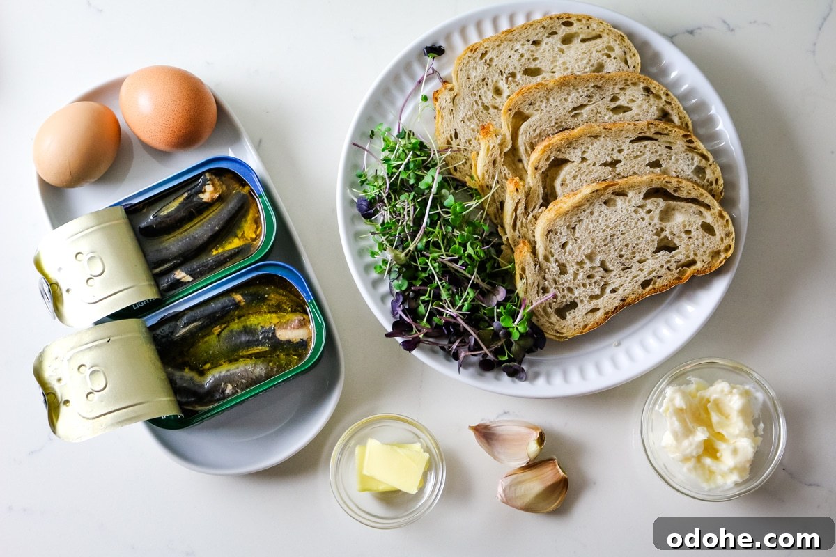Sardine and Egg Toast Recipe for Brunch or Quick Meals 4 Eggs, sardines, herbs, and bread on a white plate, with butter and garlic mayo in a clear bowl alongside garlic cloves.