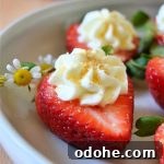 cheesecake stuffed strawberry with a daisy on a white plate