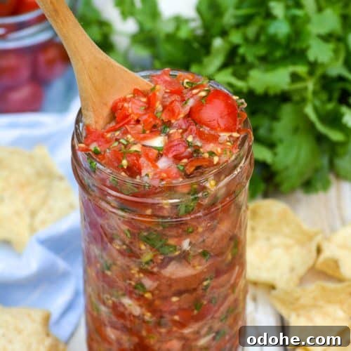 a wooden spoon stuck in a jar of cherry tomato salsa