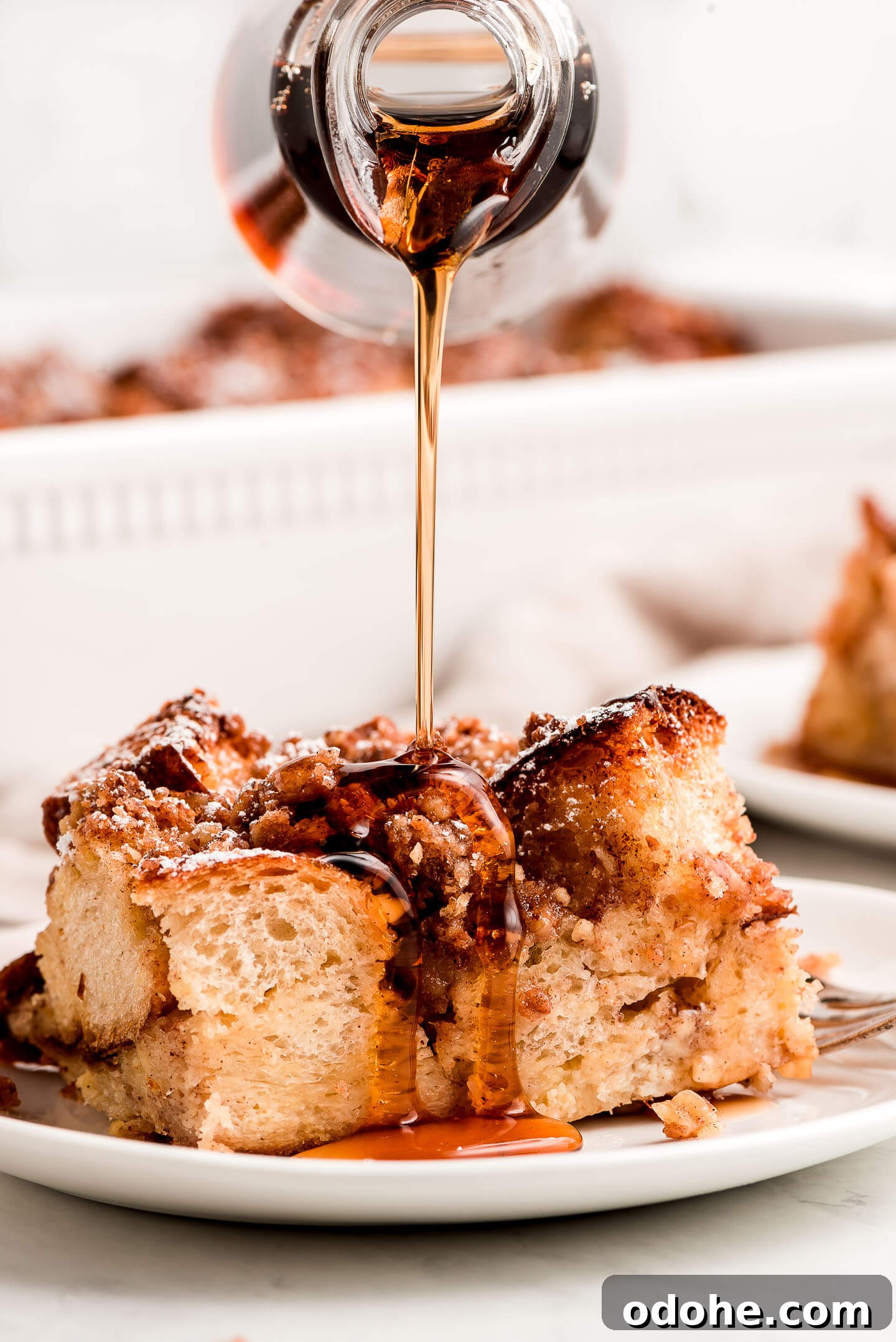 Make-Ahead Overnight French Toast Casserole Recipe 2 Maple syrup streaming down out of a bottle onto a slice of French Toast Casserole.