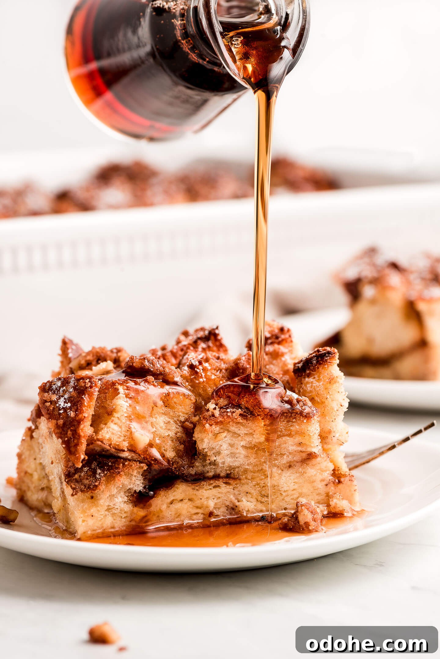 Make-Ahead Overnight French Toast Casserole Recipe 7 Pouring maple syrup over a piece of Overnight French Toast Bake.