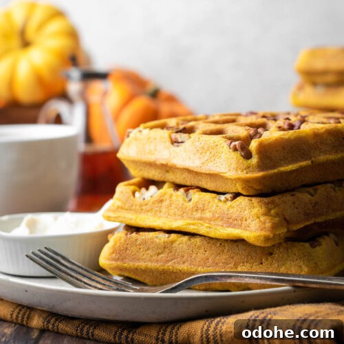 A stack of three gluten free pumpkin waffles on a serving plate.