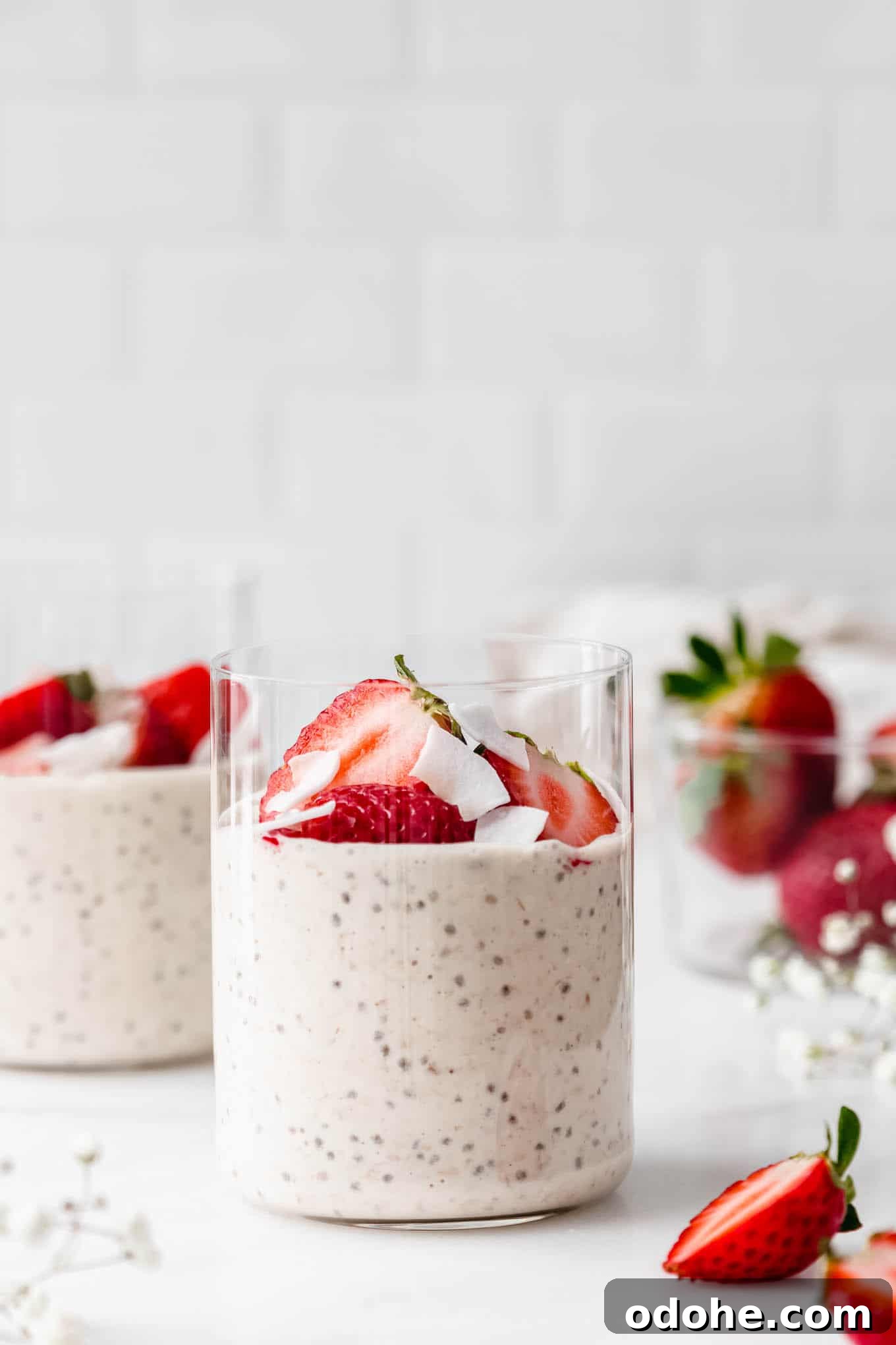two cups of protein overnight oats with strawberries and coconut flakes