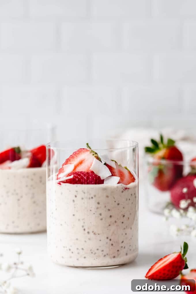 two cups of protein overnight oats with strawberries and coconut flakes