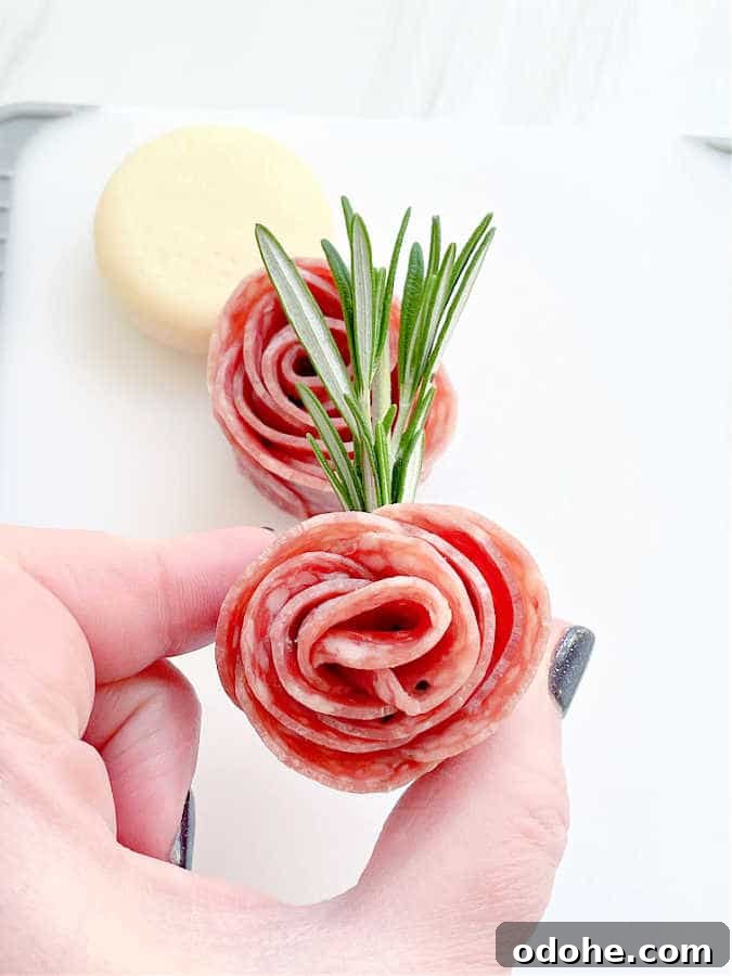 Create a Salami Rose: Step-by-Step Guide for Party Platters 7 showing a salami rosebud secured with a sprig of rosemary