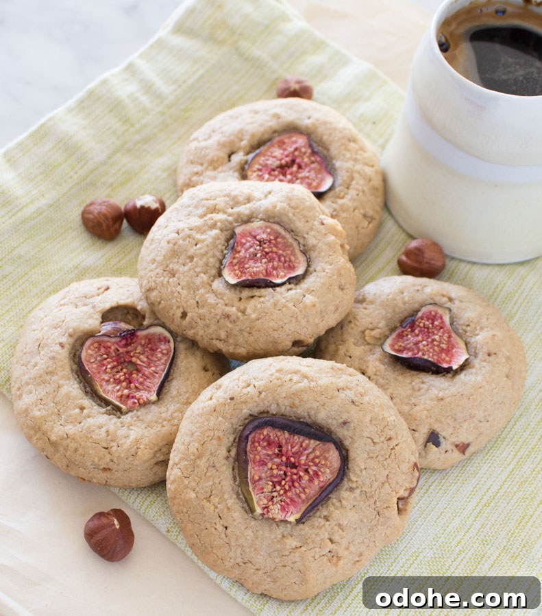 Five Fig Tahini Cookies on a napkin with hazelnuts and a small cup of coffee.