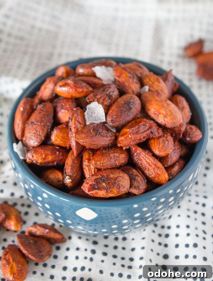 Small bowl of Harissa Roasted Almonds topped with flaky sea salt.