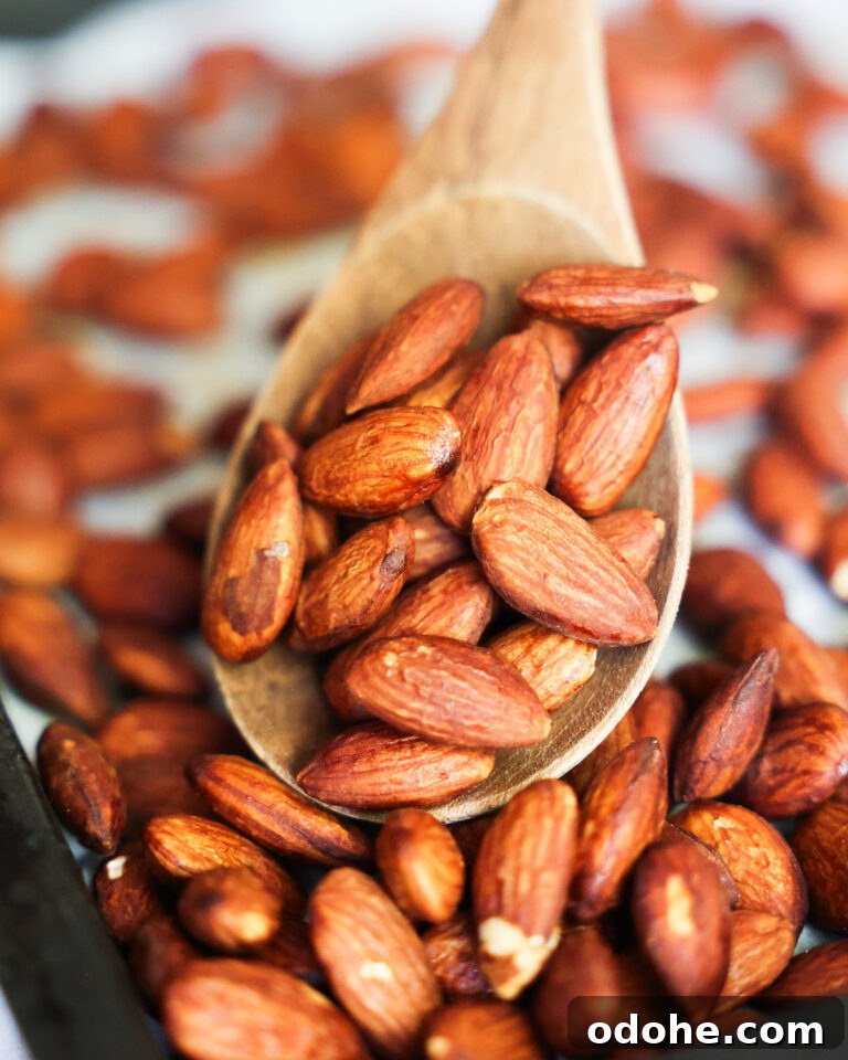 Spoon scooping Tamari Almonds off a pan.