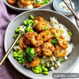 Mongolian Shrimp and Broccoli Stir-Fry Recipe 9 Mongolian shrimp in a grey bowl with edamame and a gold fork.