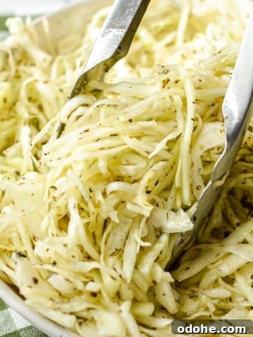 Tongs taking a portion of coleslaw.