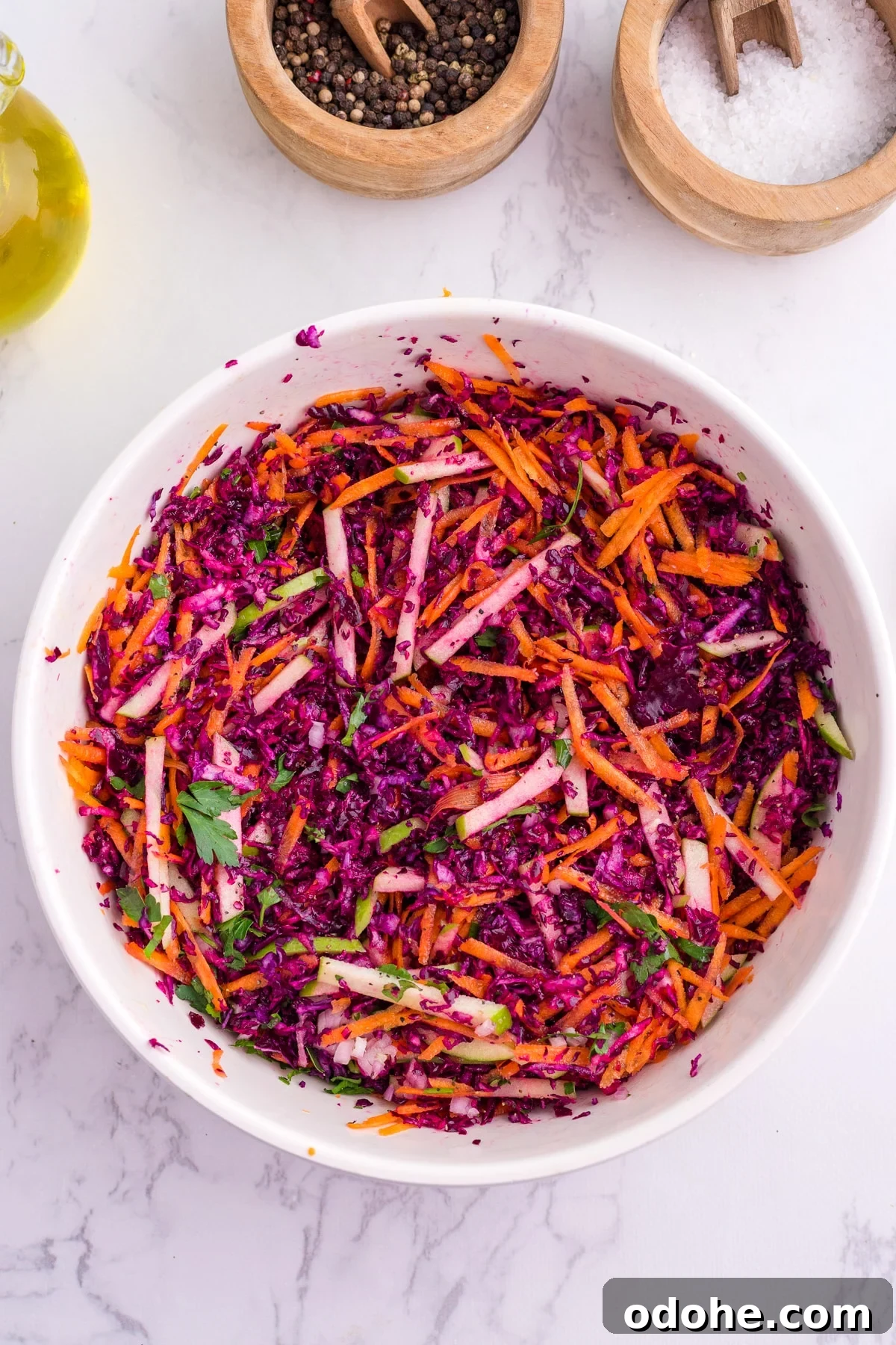 Crunchy Cabbage and Carrot Salad with Zesty Dressing 5 A white serving bowl with cabbage and carrot slaw, dressed with olive oil.