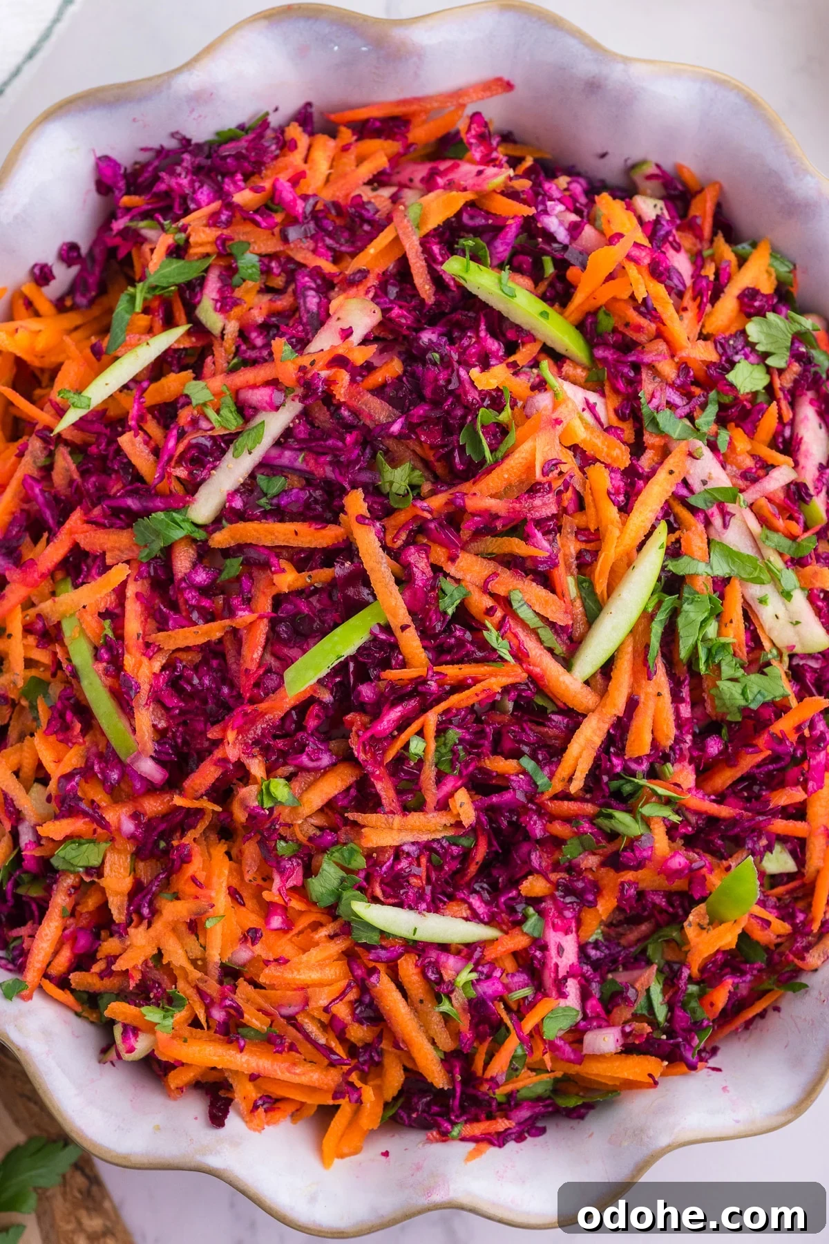 Crunchy Cabbage and Carrot Salad with Zesty Dressing 6 Cabbage and carrot slaw with green apple and parsley in a serving bowl.