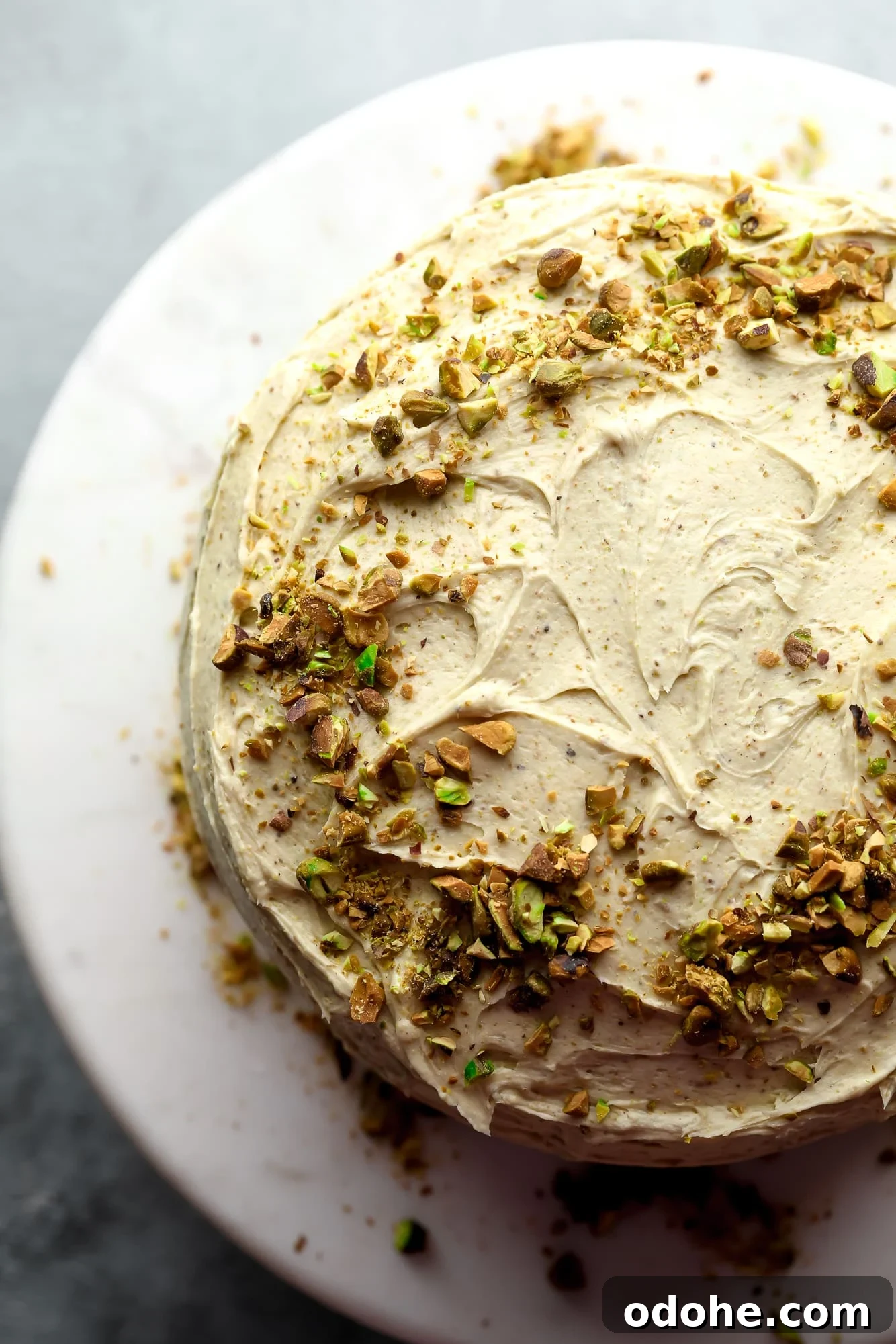 vegan pistachio cake decorated with pistachio frosting and crushed pistachios.