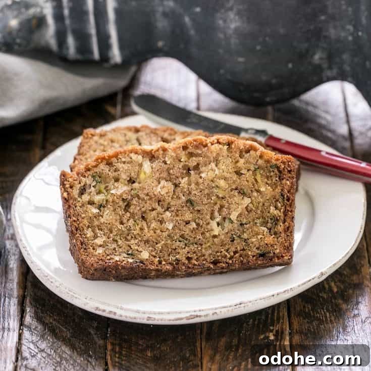 Sliced zucchini bread recipe on a white plate with a red handled knife