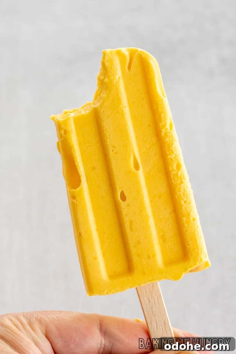 Homemade Mango Popsicle Recipe — Creamy & Refreshing 2 hand holding up mango popsicle