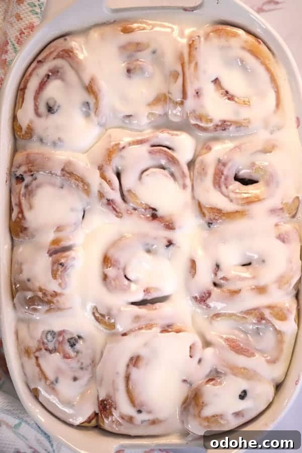 Baked cinnamon rolls covered with icing in a baking dish.