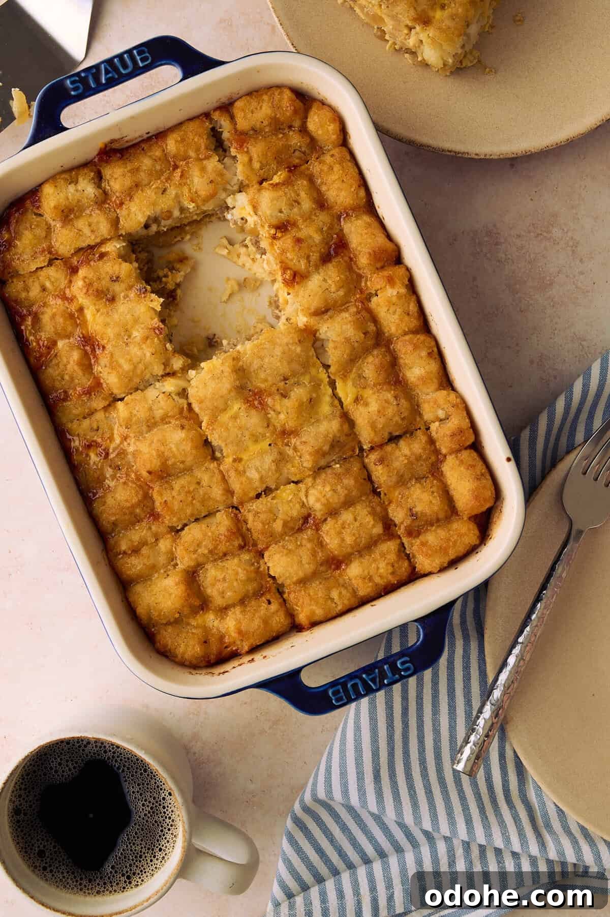 Tater Tot Breakfast Casserole Recipe for Brunch Crowd 2 A square is taken out of the tater tot casserole next to a mug of coffee.