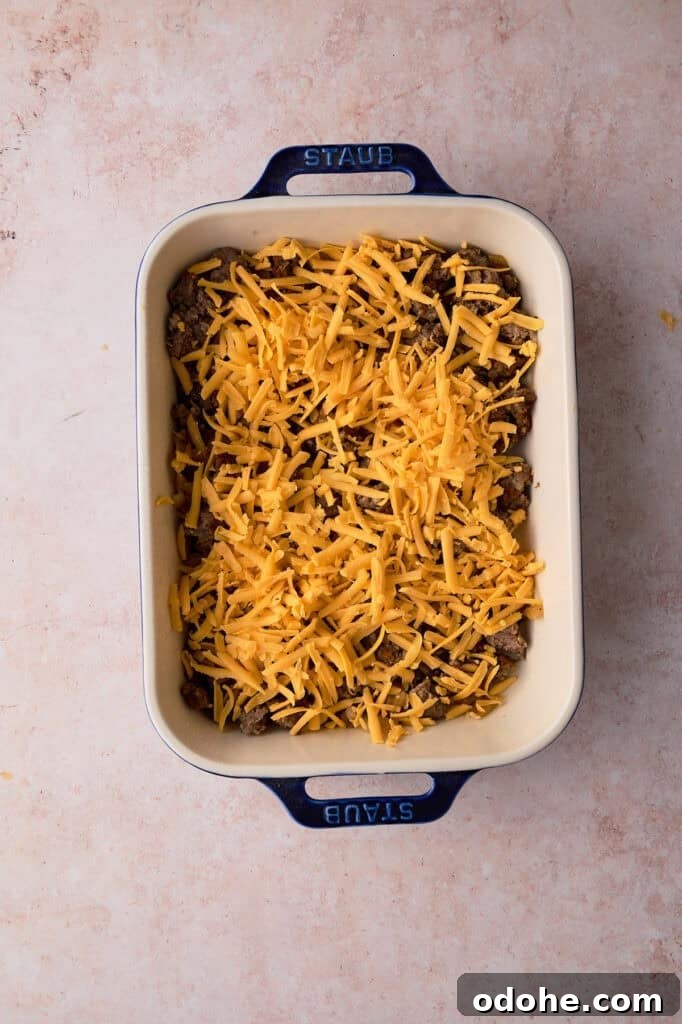 Tater Tot Breakfast Casserole Recipe for Brunch Crowd 5 Cheddar cheese is sprinkled over the sausage in the baking dish.