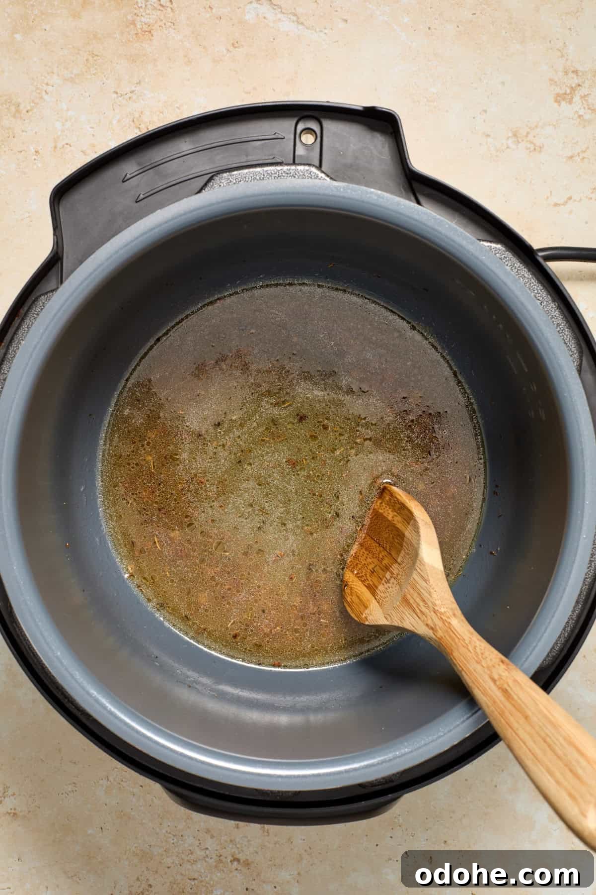 Perfect Instant Pot Pork Tenderloin Recipe for Juicy Results 8 Deglazed instant pot with broth and wooden spoon.