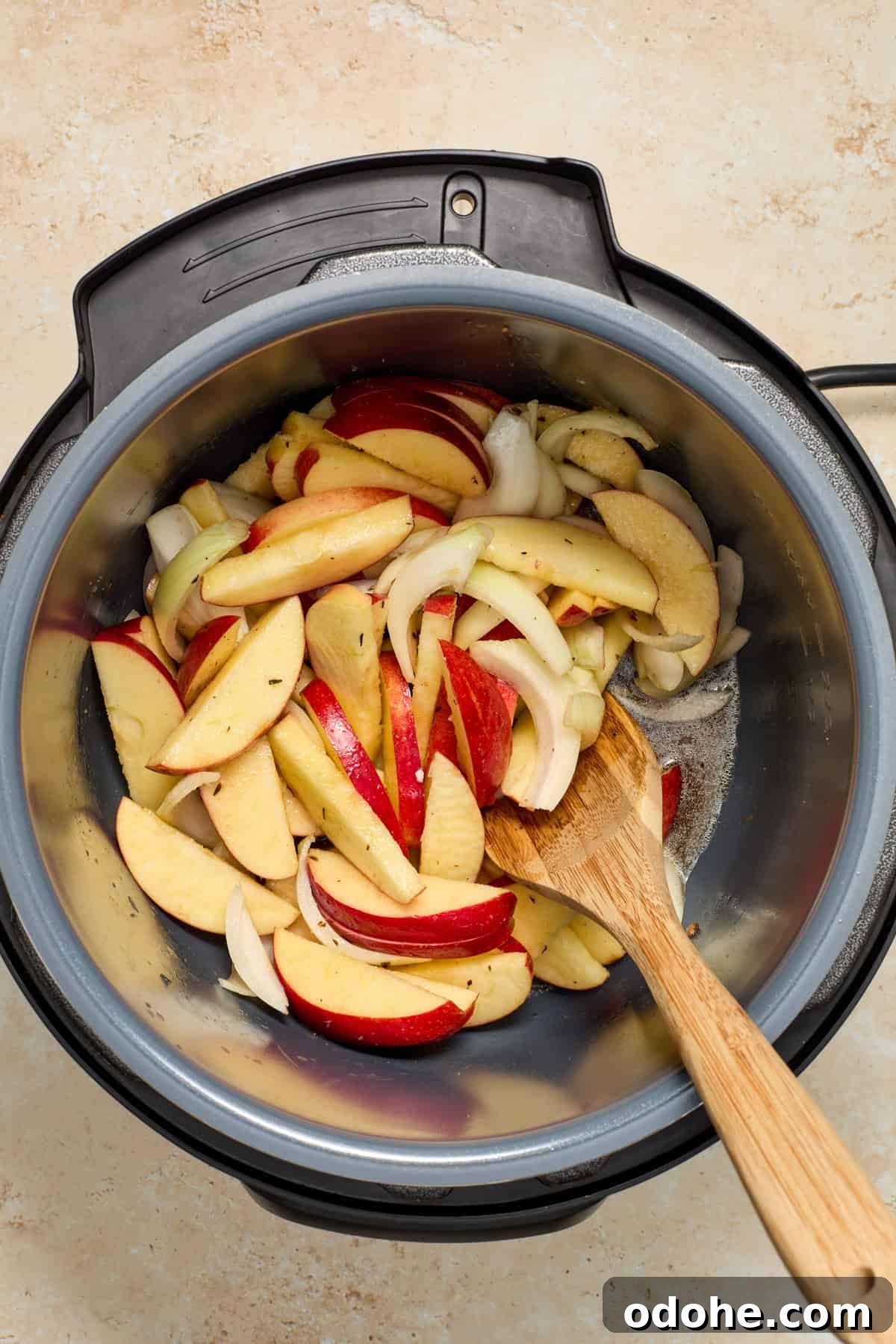 Perfect Instant Pot Pork Tenderloin Recipe for Juicy Results 9 Apples, onion, butter and brown sugar added to pot with wooden spoon.