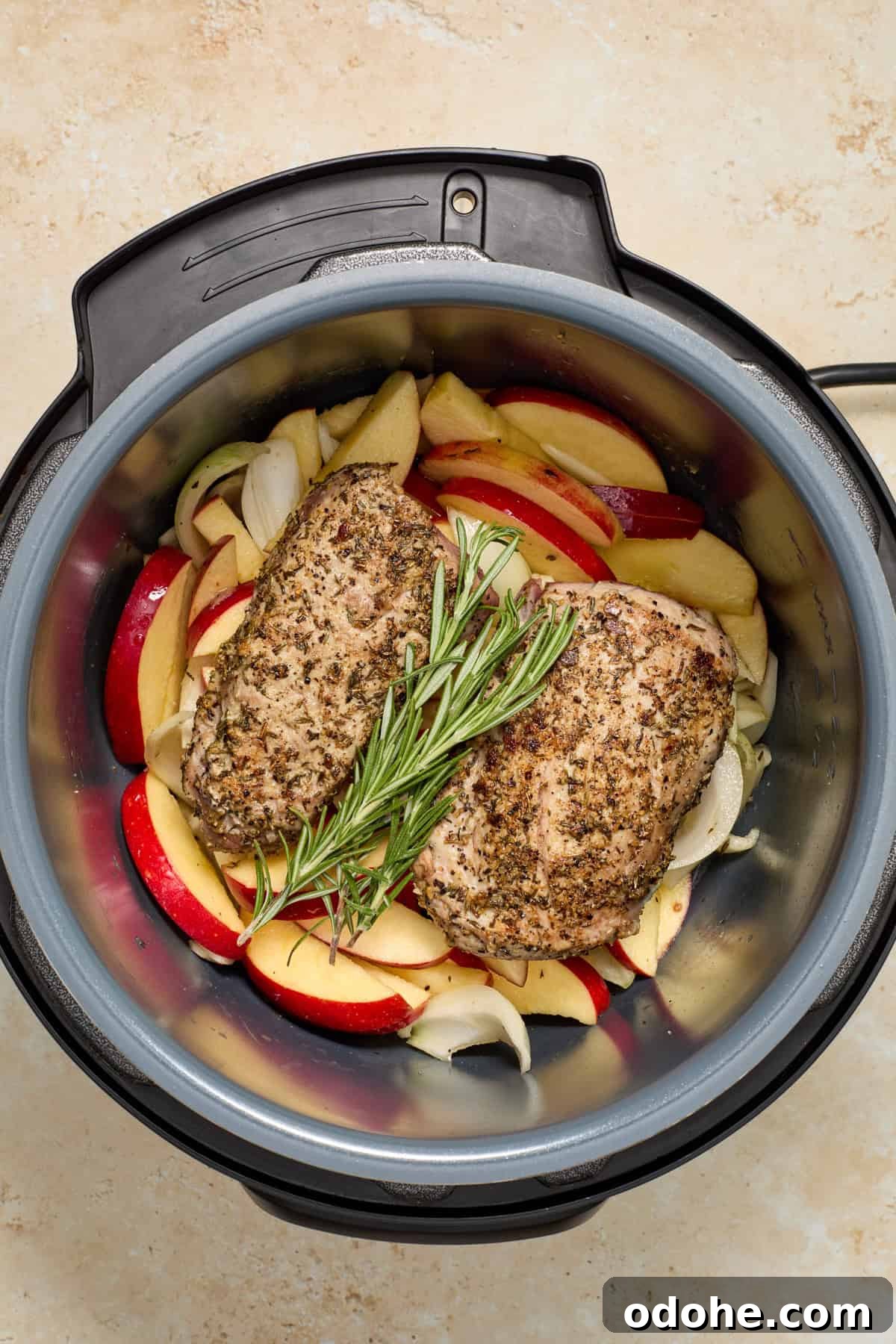 Perfect Instant Pot Pork Tenderloin Recipe for Juicy Results 10 Seared pork tenderloin on top of apples and onions with rosemary sprig in pressure cooker.