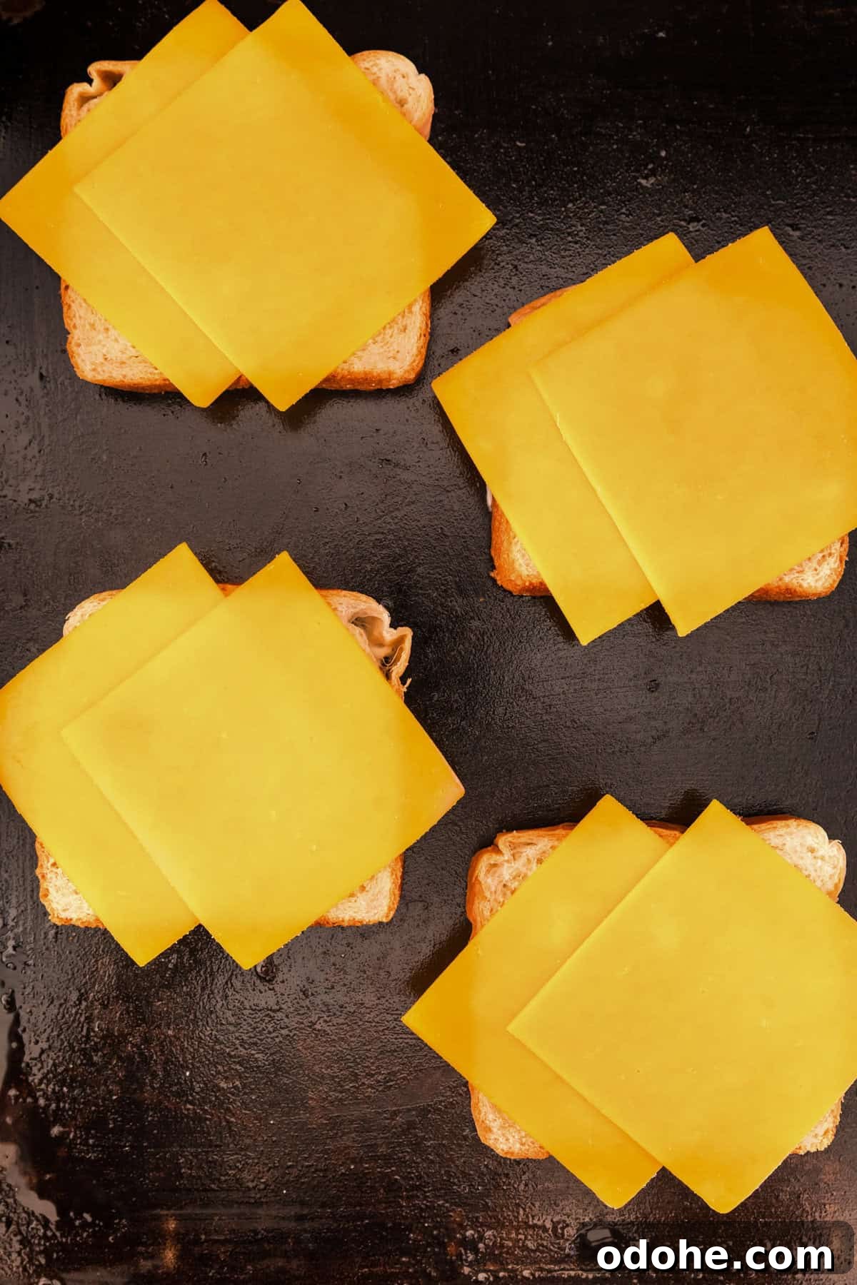 Perfect Grilled Cheese on a Blackstone Griddle: Melted & Crispy 6 Adding two slices of cheddar cheese to bread on griddle for Blackstone Grilled Cheese