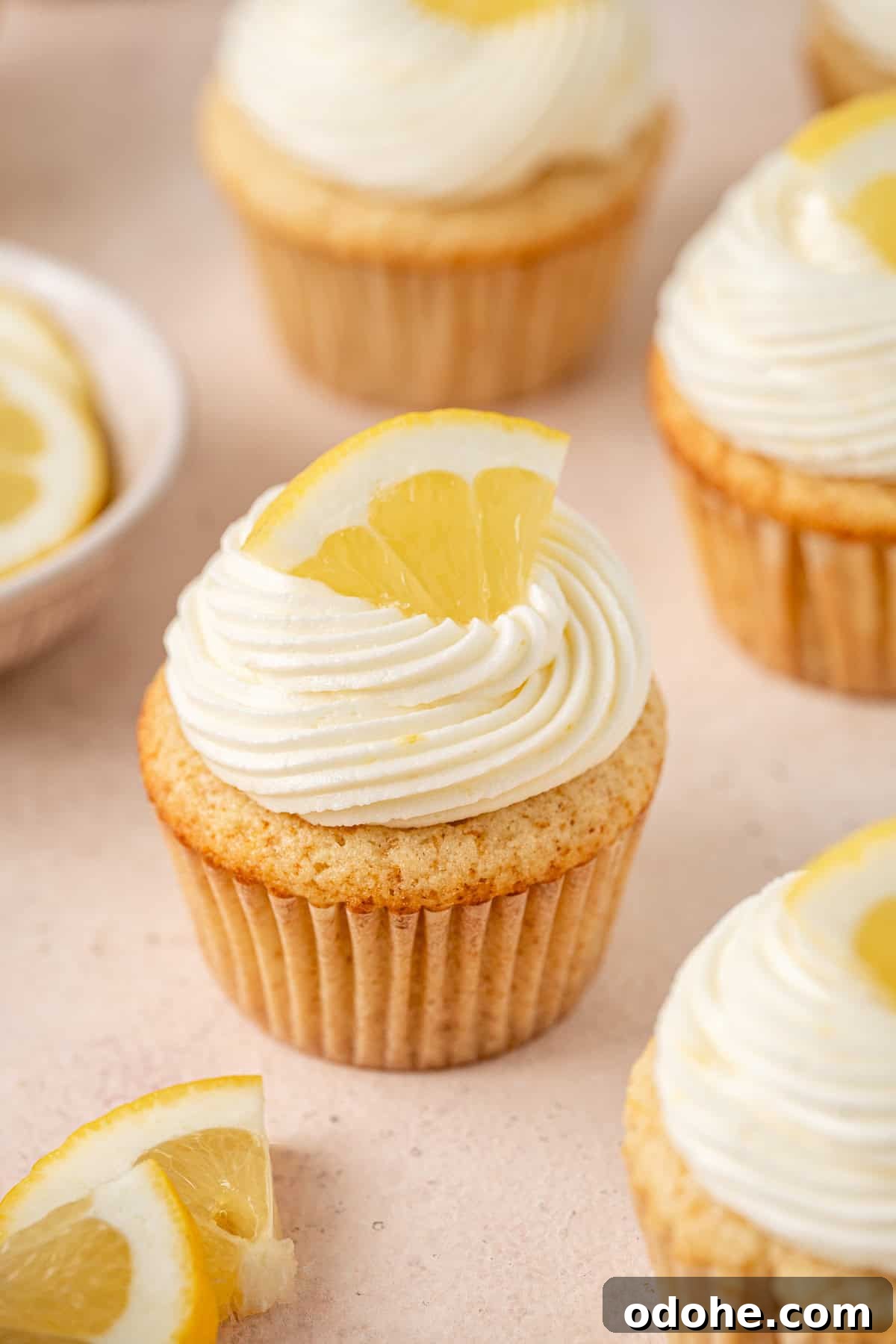 Dairy and gluten free lemon cupcakes with buttercream frosting, topped with a wedge of fresh lemon.