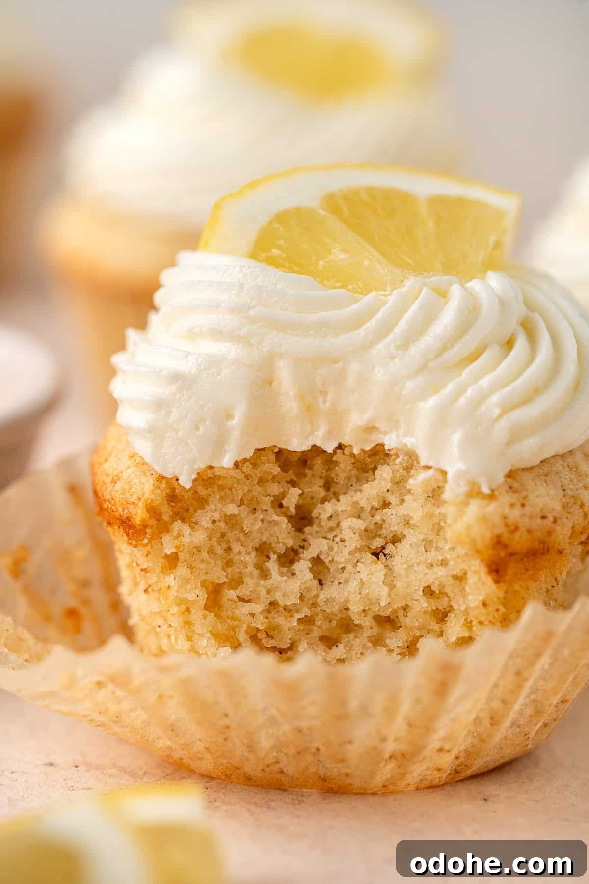Close up of a lemon cupcake with a bite taken.