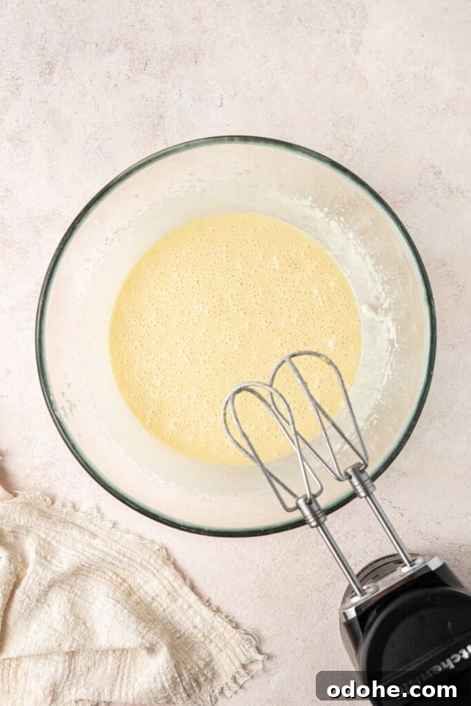 The wet ingredients mixed together in a glass bowl with electric beaters.