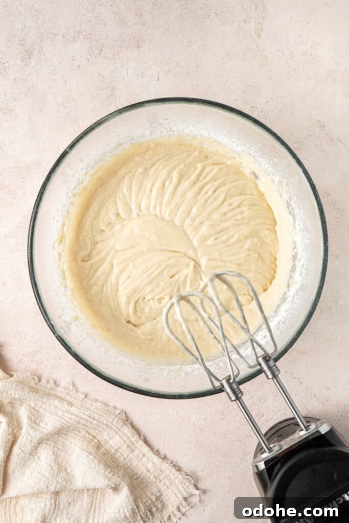 Mixing together the cupcake batter in a glass bowl with electric beaters.
