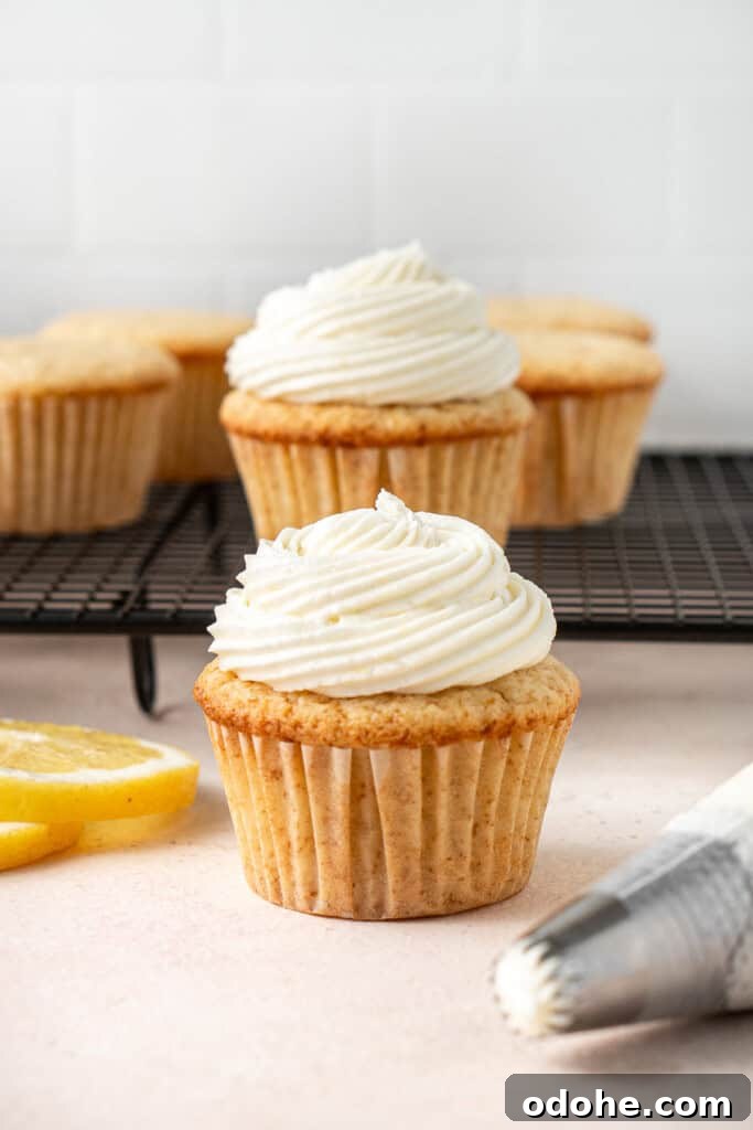 Piping swirls of lemon buttercream frosting onto lemon cupcakes.