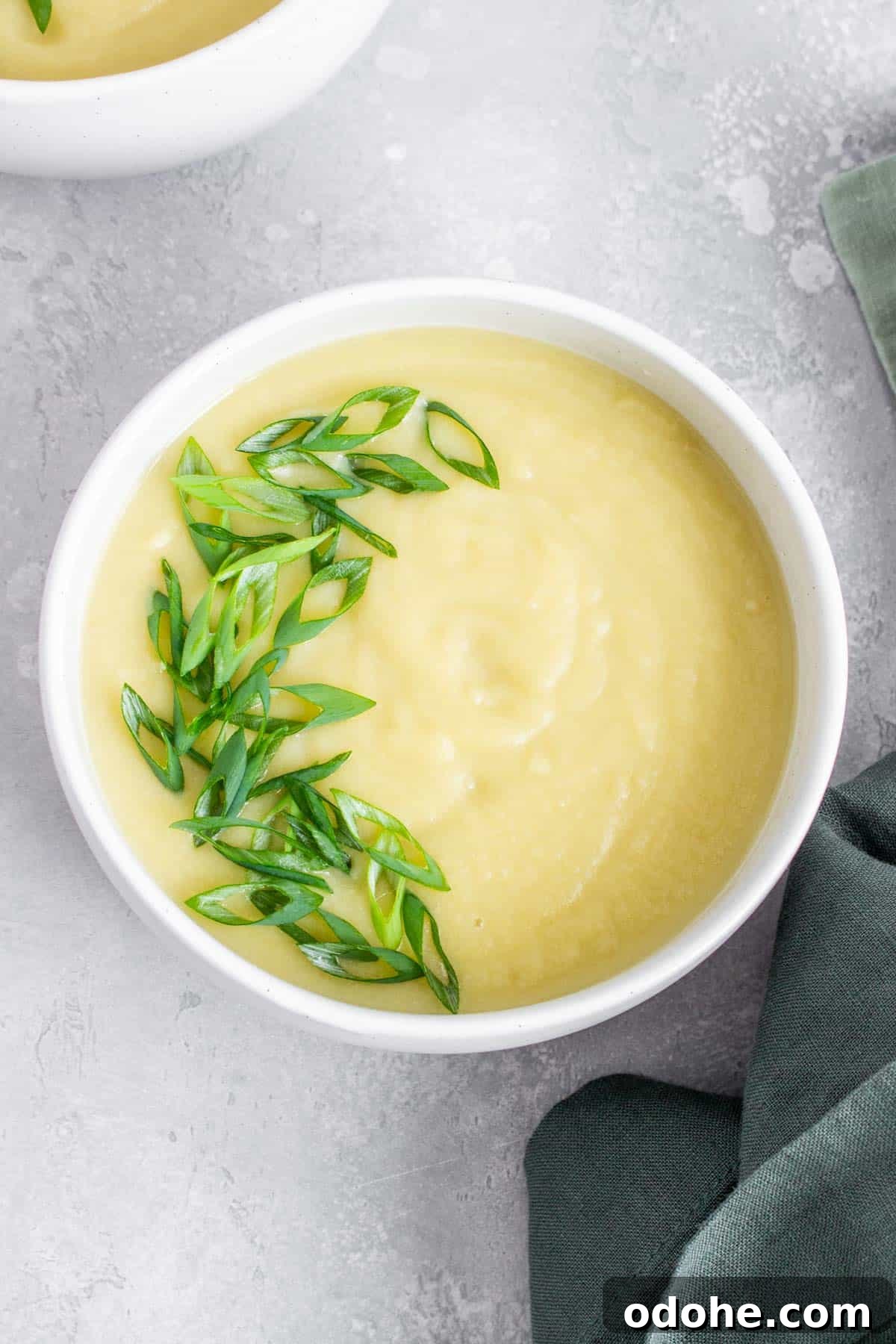 Creamless Potato and Leek Soup: Light, Velvety Recipe 7 Overhead view of a bowl of potato leek soup with green onion garnish.