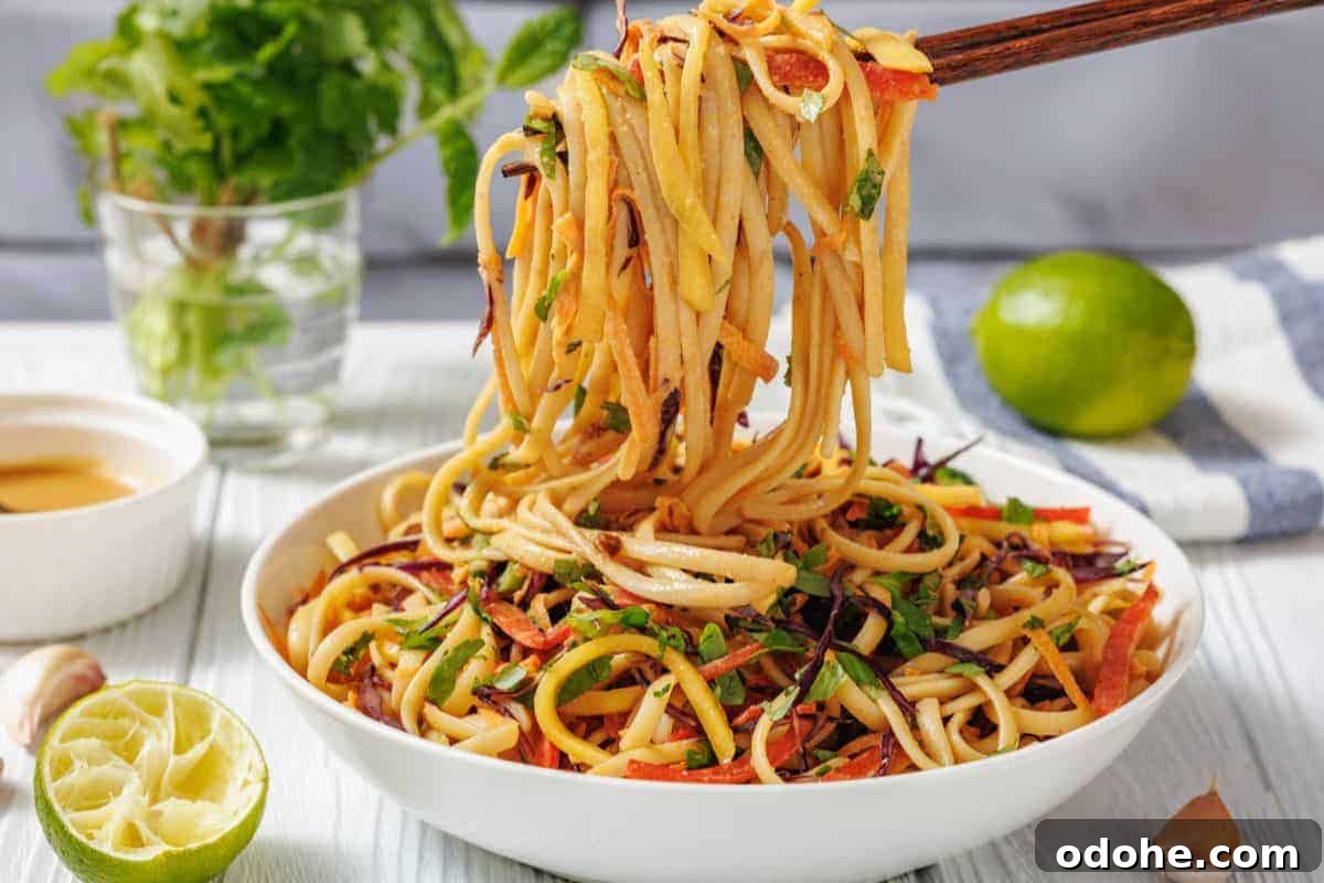 31 Memorial Day Recipes to Start Cookout Season Right 12 A bowl of Thai Noodle Salad with Mango and Spicy Peanut Dressing is lifted by chopsticks.