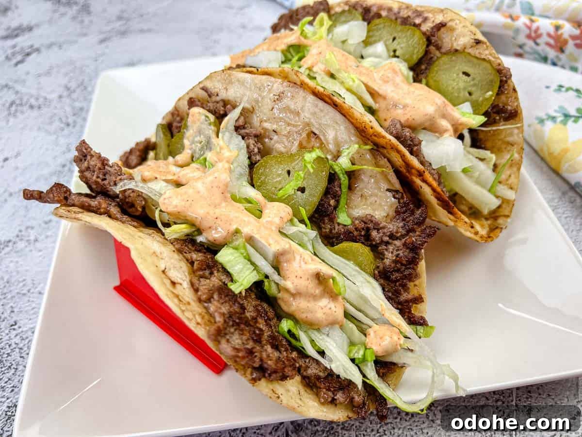 31 Memorial Day Recipes to Start Cookout Season Right 13 Two Big Mac tacos filled with ground beef, shredded lettuce, and pickles, and drizzled with a creamy sauce, placed on a white plate.