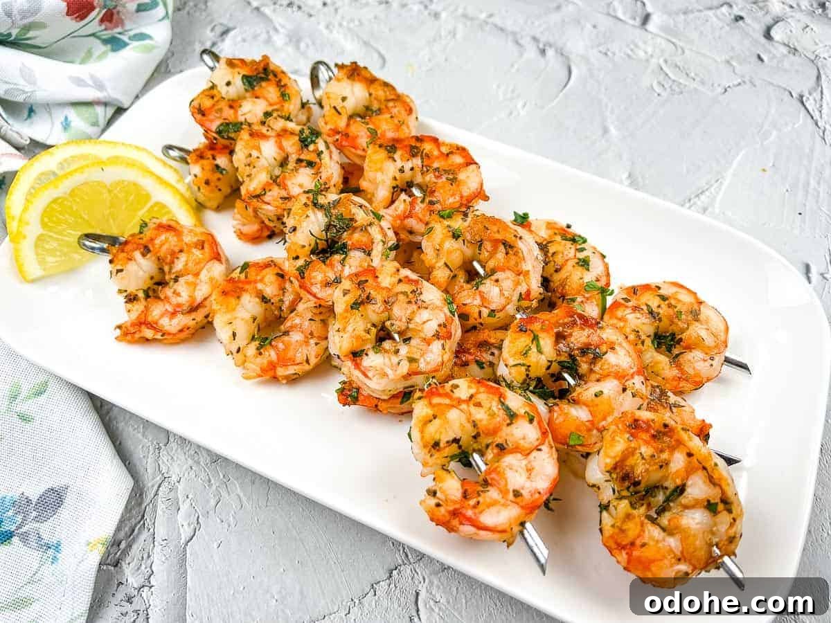 31 Memorial Day Recipes to Start Cookout Season Right 14 Mediterranean Grilled Shrimps on a white plate with lemon wedges.